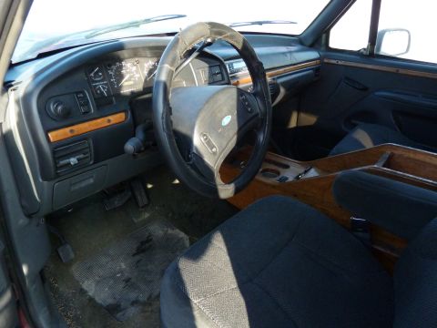 1993 Ford C-150 (Centurion Conversions) - The interior of a truck shows a dashboard with gauges, wood trim accents, and dark fabric seats.