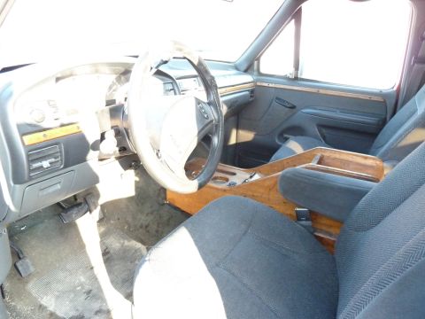 1993 Ford C-150 (Centurion Conversions) - The interior of a truck features wood grain accents on the dashboard and center console, along with cloth seats.