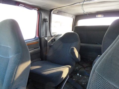 1993 Ford C-150 (Centurion Conversions) - The interior of the van shows multiple rows of seats and a cluttered floor.