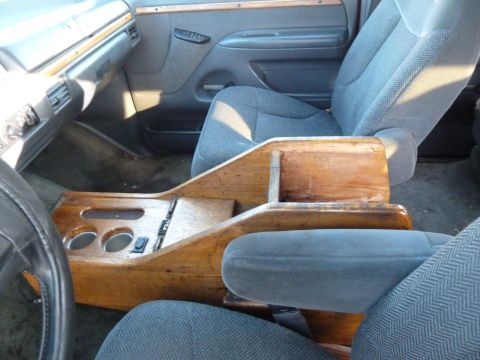 1993 Ford C-150 (Centurion Conversions) - The interior of a van shows cloth seats and a custom wooden center console with cup holders.
