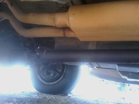 1993 Ford C-150 (Centurion Conversions) - Underside view of the exhaust system and a wheel, showing the vehicle's undercarriage components.