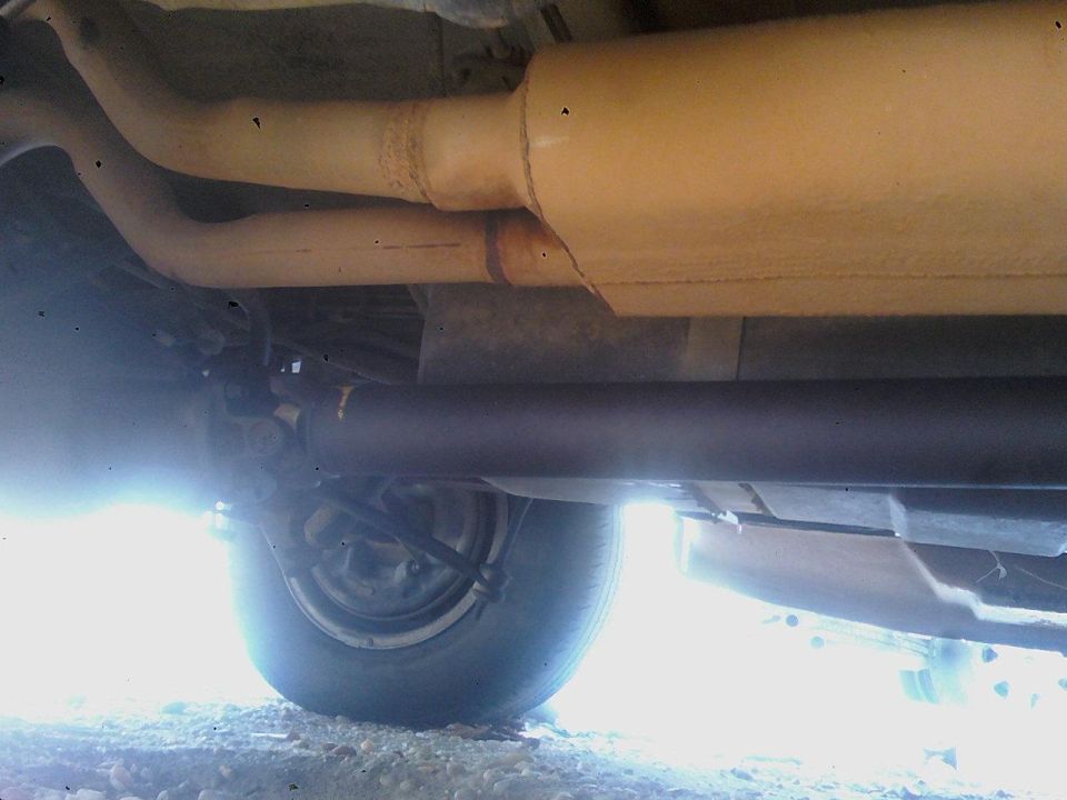 Underbody view of exhaust pipes and a rear wheel