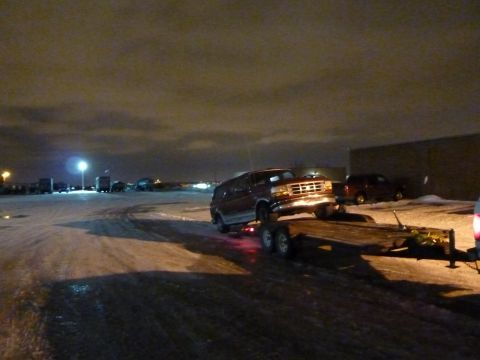1993 Ford C-150 (Centurion Conversions) - A red van is loaded onto a trailer at night, with a distinctive grille suggesting a 1992 model year.