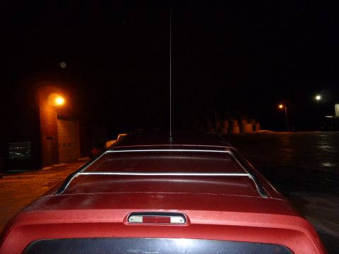 1993 Ford C-150 (Centurion Conversions) - The rear of a red SUV is visible at night, with a tall antenna extending from the roof.