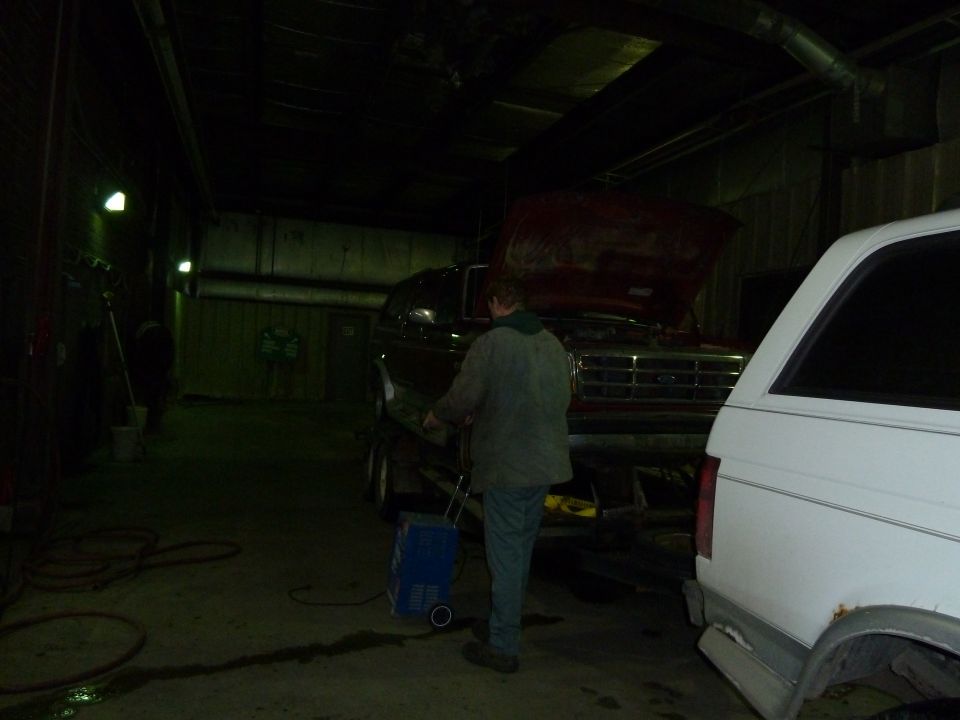 Ford F-Series truck with hood open on a trailer, white vehicle to the right