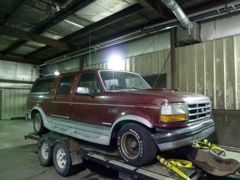 1993 Ford C-150 (Centurion Conversions) - This maroon SUV, likely a 1992 model based on its grille, is secured to a trailer for transport.