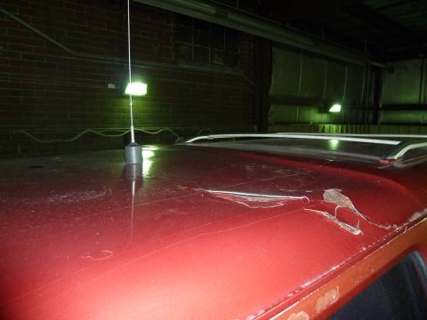 1993 Ford C-150 (Centurion Conversions) - The roof of a red vehicle shows significant damage and rust.