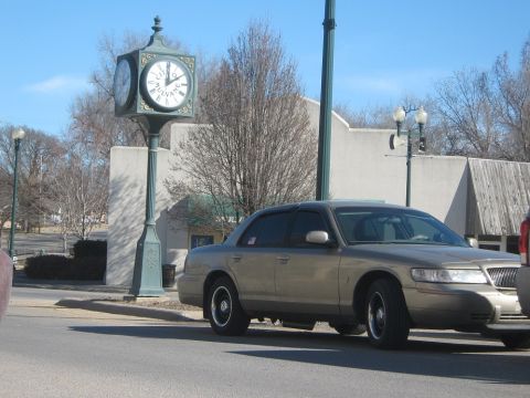 2000 Mercury Grand Marquis - A gold Mercury Grand Marquis is parked on the street next to a large clock tower.