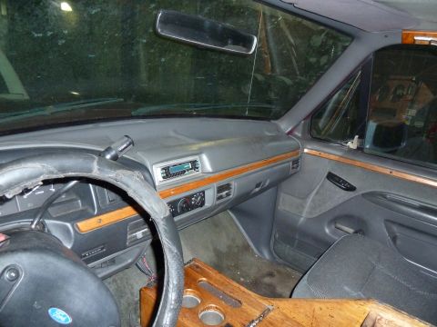 1993 Ford C-150 (Centurion Conversions) - The interior of a 1993 Ford C-150 (Centurion Conversions) features a wood-trimmed dashboard and a worn steering wheel.