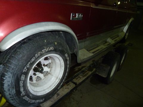 1993 Ford C-150 (Centurion Conversions) - A red pickup truck is loaded onto a trailer, showing its side profile and tire.