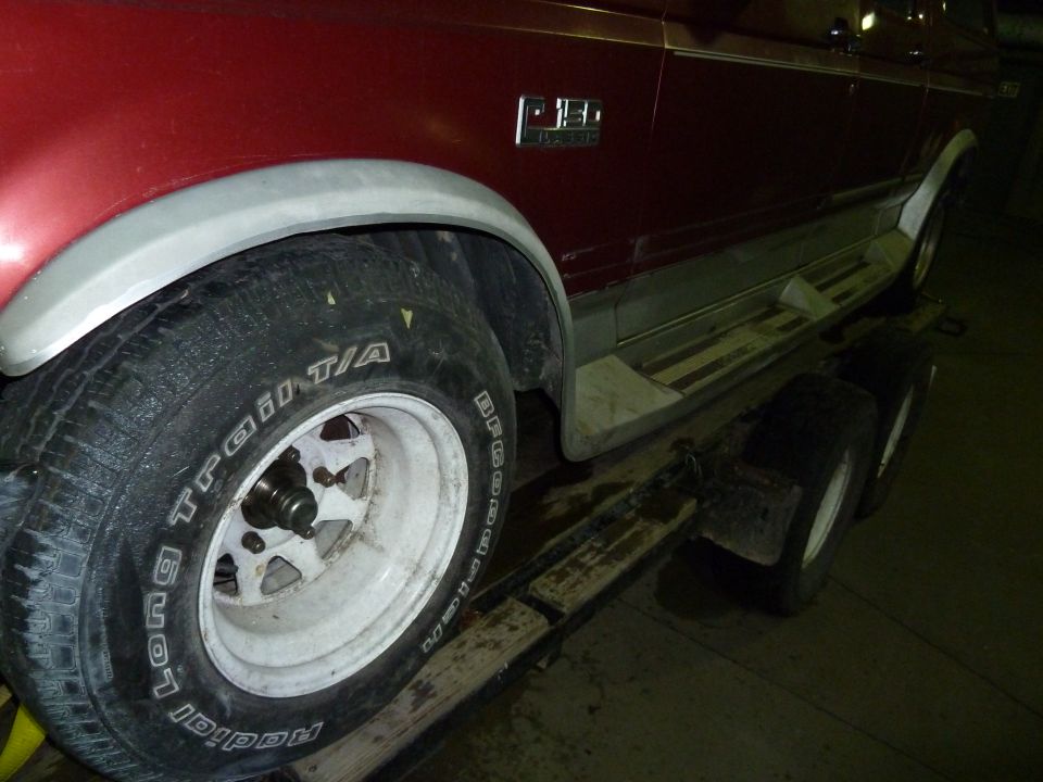 Side view of a red pickup truck with a 'F150' badge, on a trailer