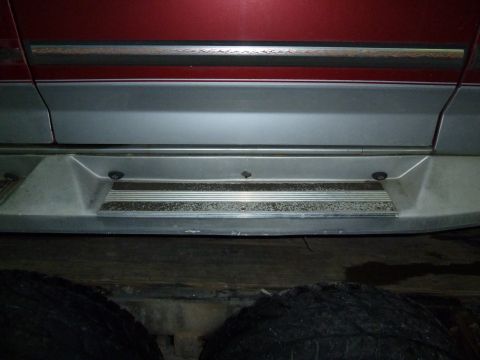 1993 Ford C-150 (Centurion Conversions) - Close-up of a vehicle's side step and lower body panel, with visible dirt and wear.