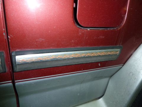 1993 Ford C-150 (Centurion Conversions) - Close-up of a red vehicle's side panel, chrome trim with a flame decal and a two-tone lower body.