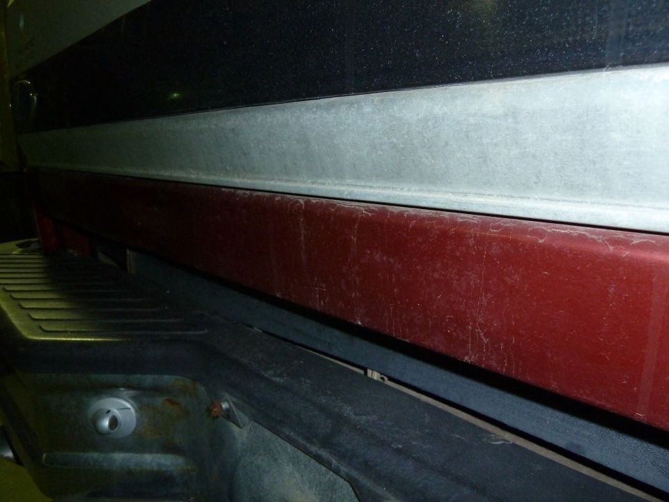 Close-up of a red tailgate and black bumper on a truck