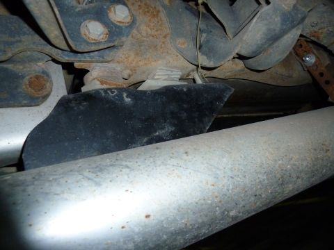1993 Ford C-150 (Centurion Conversions) - Close-up view of the undercarriage, focusing on the exhaust system and rusted suspension parts.