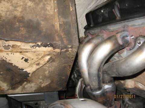 1961 International Scout 800 - Close-up view of the exhaust manifold and part of the vehicle's chassis, showing signs of rust and wear.