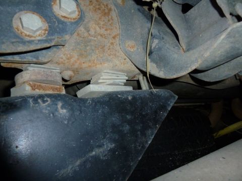 1993 Ford C-150 (Centurion Conversions) - Close-up of vehicle undercarriage components, including spacers and suspension parts, with visible rust and wear.