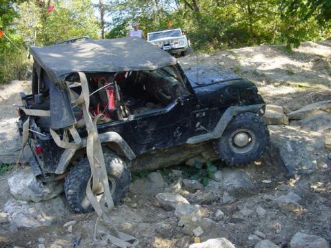 1992 Ford Bronco - A black Jeep Wrangler navigates a rocky trail, while another vehicle is visible behind it.