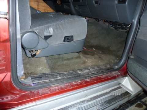 1993 Ford C-150 (Centurion Conversions) - The interior of a truck shows the driver's seat and the area around the door jamb, with exposed wiring beneath the dashboard.