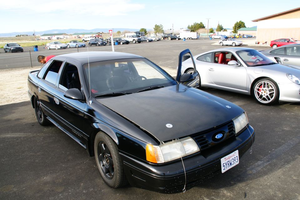 Black sedan with racing modifications, front 3/4 view. License plate 5YRW393