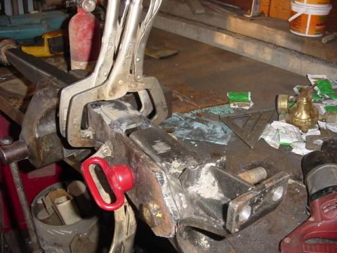 1992 Ford Bronco - A metal part is secured in a vise with locking pliers, surrounded by various tools and workshop items.