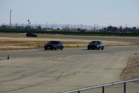 1995 Ford Taurus - Two 1995 Ford Tauruses are seen on a race track under a clear sky.