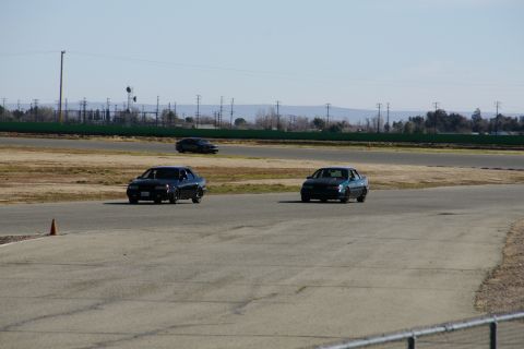 1995 Ford Taurus - Three Ford Taurus sedans compete on a race track, with one in the foreground and two further back.
