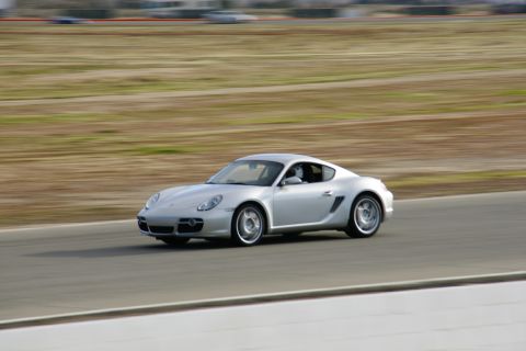 1995 Ford Taurus - Silver Porsche Cayman on a racetrack with motion blur.