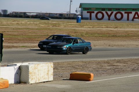 1995 Ford Taurus - Teal 1995 Ford Taurus seen on a racetrack with another car in the background.