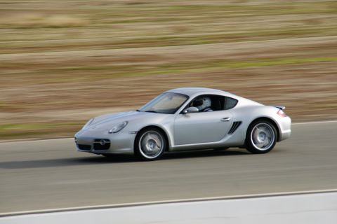 1995 Ford Taurus - Silver Porsche Cayman on a race track, driver visible in helmet.