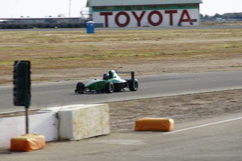 1995 Ford Taurus - A green open-wheel race car drives on a track with a large TOYOTA sign visible in the background.