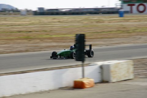 1995 Ford Taurus - A green open-wheel race car speeds around a track, captured in motion.