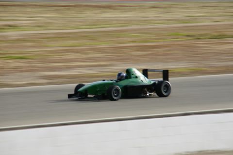 1995 Ford Taurus - Open-wheel race car captured in motion on a race track with a blurred background.