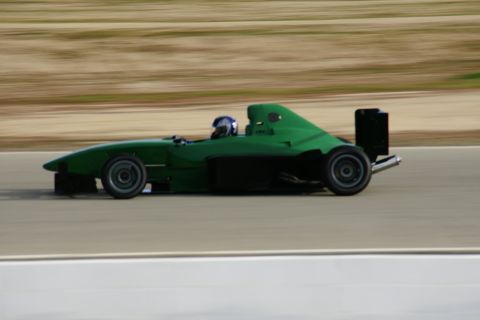 1995 Ford Taurus - A green race car speeds down a track, blurring the background.
