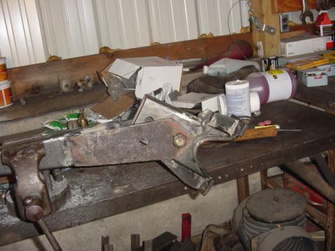 1992 Ford Bronco - A metal component is secured in a vise on a workbench, surrounded by shop supplies and tools.