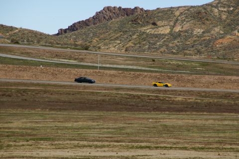 1995 Ford Taurus - Two cars travel along a highway that winds through a dry, hilly landscape under a clear sky.