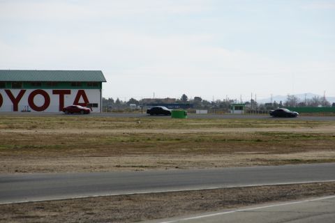 1995 Ford Taurus - Cars race on a track near a building with large TOYOTA lettering.