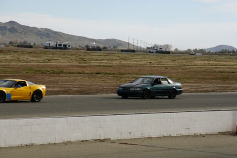 1995 Ford Taurus - Two cars are on a racetrack with mountains and RVs in the background.