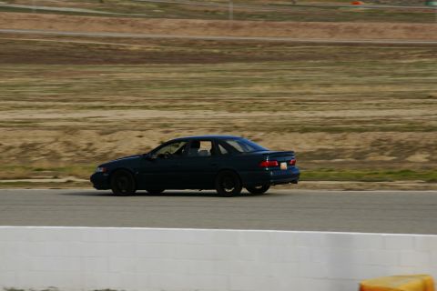 1995 Ford Taurus - Dark sedan on race track, side view. Appears to be a 1995 Ford Taurus.
