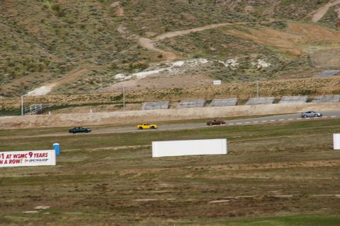 1995 Ford Taurus - Several cars race on a track with a mountainous backdrop. A yellow sports car is visible in the mid-ground.