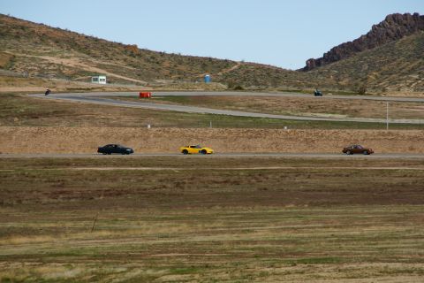 1995 Ford Taurus - Multiple vehicles are visible on a racetrack under a clear sky.
