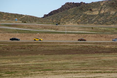 1995 Ford Taurus - Cars race on a track with arid hills in the background.