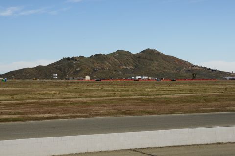 1995 Ford Taurus - A vast landscape with a mountain range under a clear blue sky, a racetrack and distant buildings.