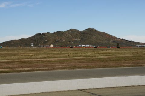 1995 Ford Taurus - A wide view of a race track and surrounding landscape with distant buildings and hills under a clear sky.