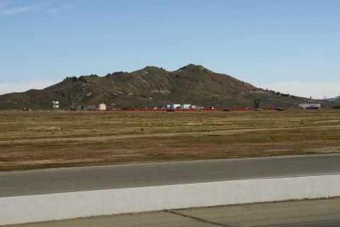 1995 Ford Taurus - A wide view of a race track and surrounding landscape, with buildings and mountains in the distance under a clear blue sky.