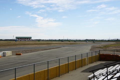 1995 Ford Taurus - A race track scene with several cars driving and a building with TOYOTA branding visible in the background.