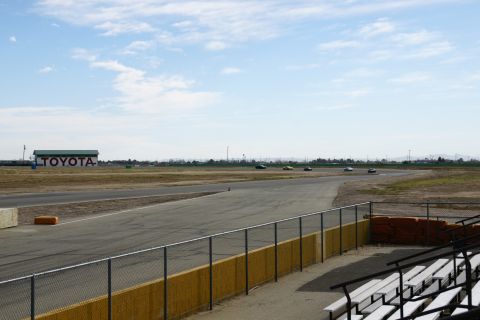 1995 Ford Taurus - Cars race on a track with a TOYOTA building visible in the background under a partly cloudy sky.
