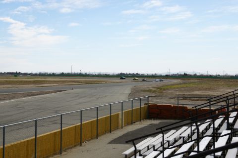 1995 Ford Taurus - Cars compete on a race track under a partly cloudy sky, viewed from the stands.