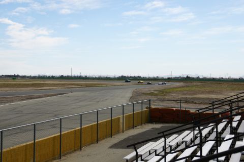 1995 Ford Taurus - Cars compete on a race track with grandstands in the foreground and a distant horizon.