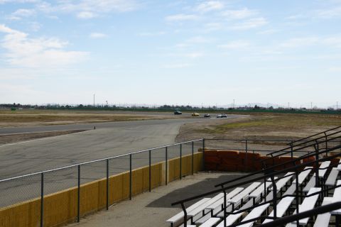 1995 Ford Taurus - Several cars are seen racing on a track, with empty grandstands visible in the foreground.
